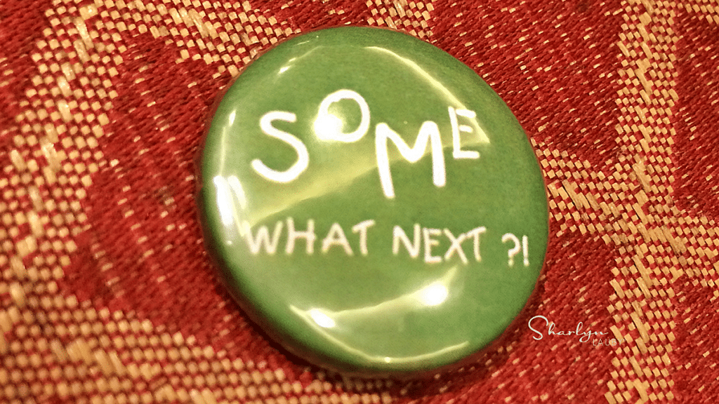 green lapel pin on a carpet saying what next for answers