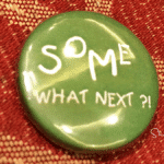 green lapel pin on a carpet saying what next for answers