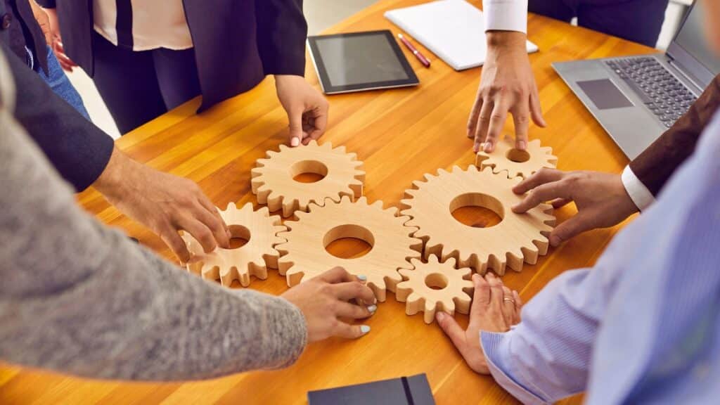 recruiting strategy meeting showing employees in office arranging gears on table top