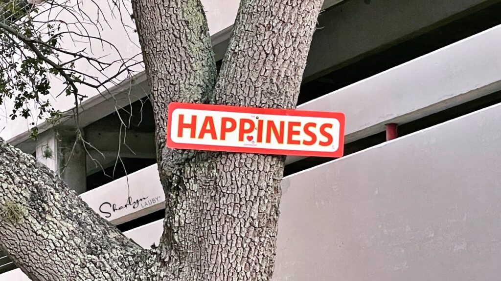 sign posted on a tree saying happiness for workplace wellbeing